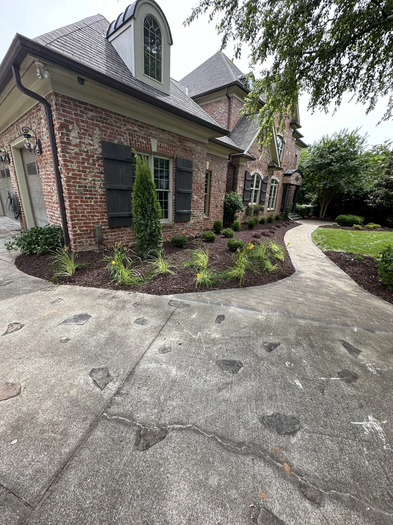 Fresh planting beds and a curved walkway beside a brick home