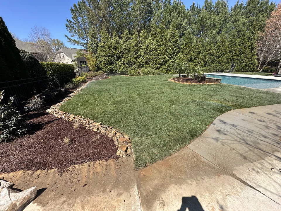 Poolside lawn edged with river rock and mulched planting beds